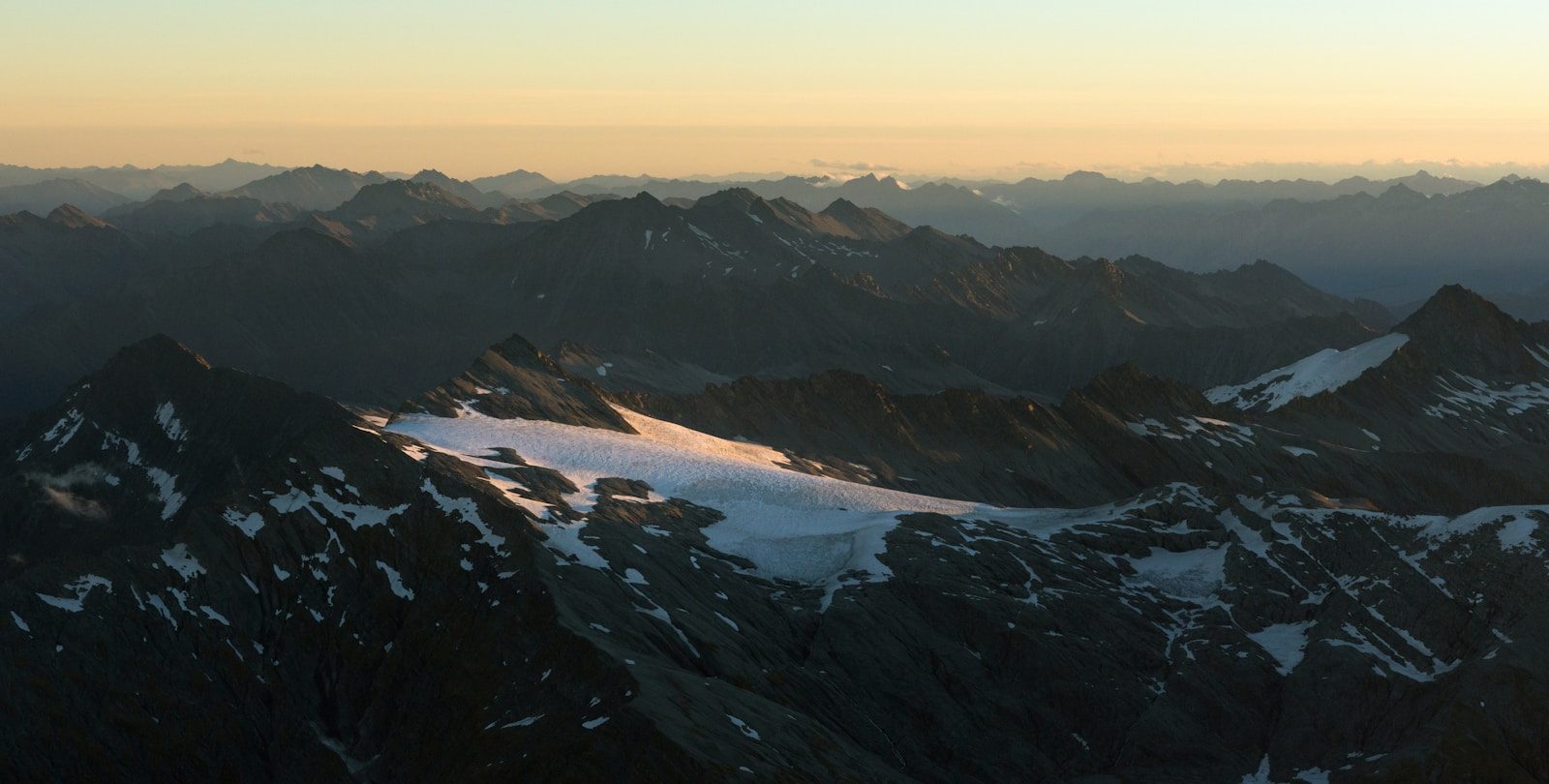Snow-capped mountains under a hazy sunset sky
